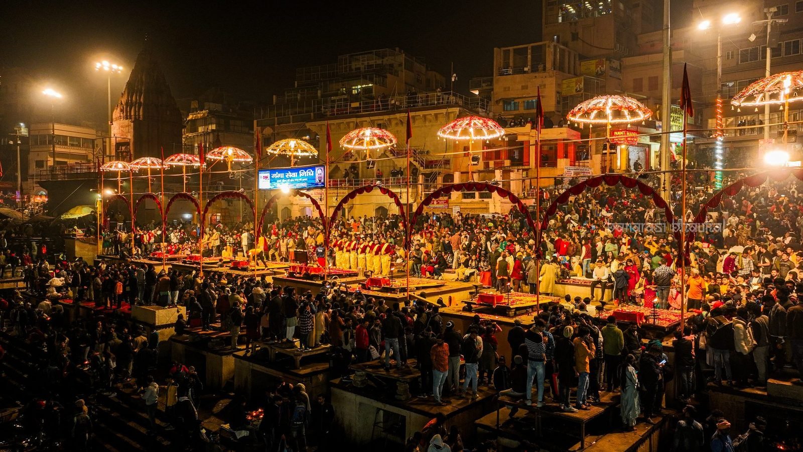 Evening Ganga aarti at Dashashwamedh Ghat, with lit umbrellas over the ghat and a large crowd watching