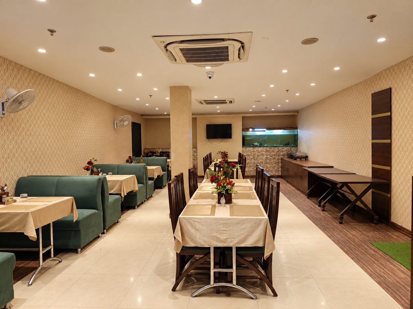 Restaurant with long dining tables, green banquettes and a buffet counter